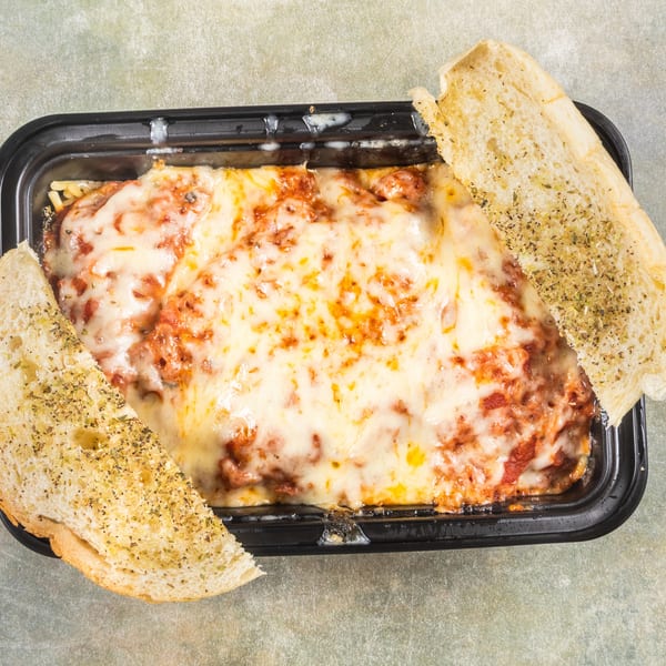 Baked spaghetti with melted cheese and marinara sauce, served with two slices of garlic bread.